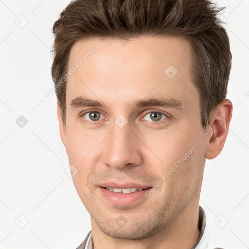 Joyful white young-adult male with short  brown hair and grey eyes