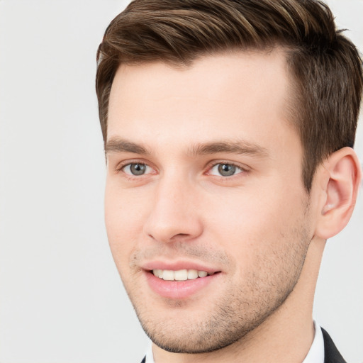 Joyful white young-adult male with short  brown hair and grey eyes