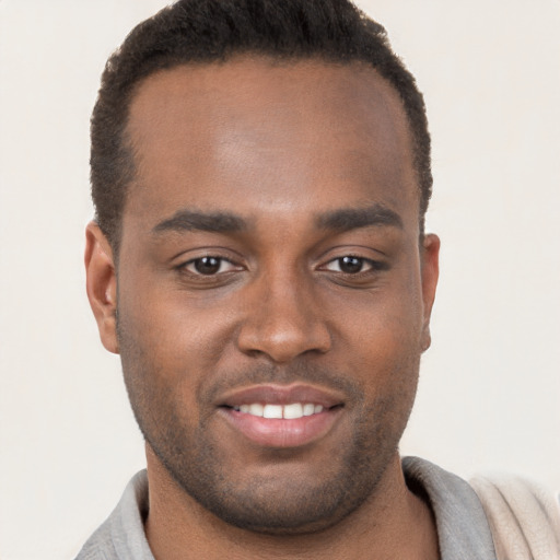 Joyful black young-adult male with short  brown hair and brown eyes