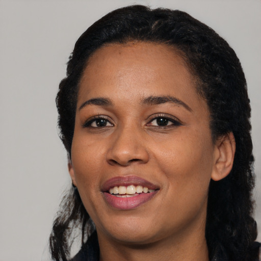 Joyful black young-adult female with long  black hair and brown eyes
