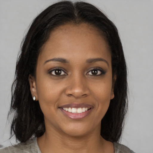 Joyful black young-adult female with long  brown hair and brown eyes