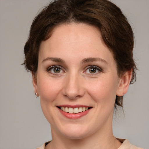 Joyful white young-adult female with medium  brown hair and green eyes