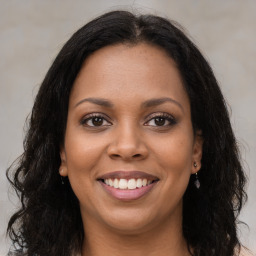 Joyful black young-adult female with long  brown hair and brown eyes