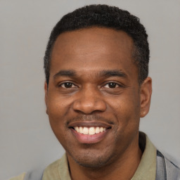 Joyful black young-adult male with short  black hair and brown eyes