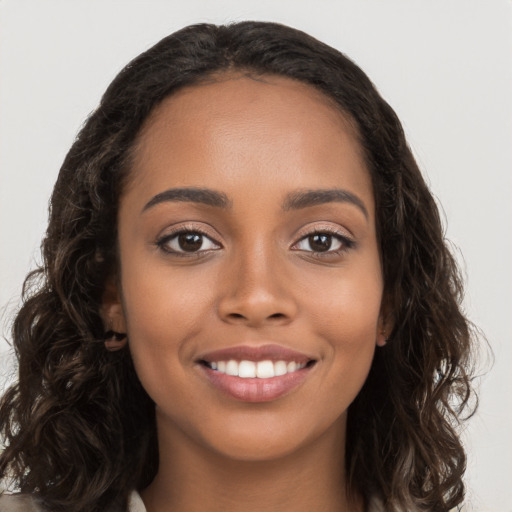 Joyful black young-adult female with long  brown hair and brown eyes