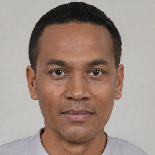Joyful black young-adult male with short  black hair and brown eyes