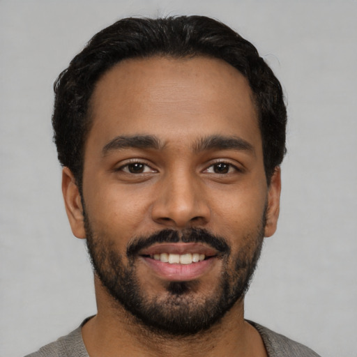 Joyful black young-adult male with short  black hair and brown eyes