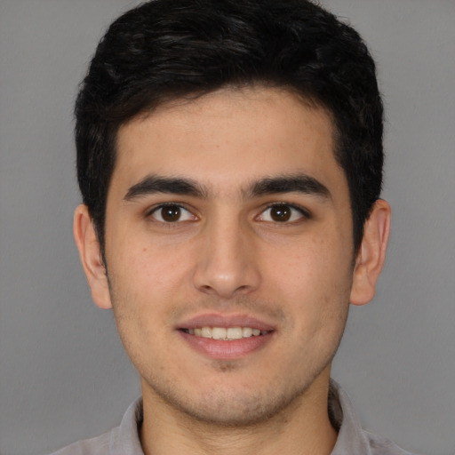 Joyful latino young-adult male with short  brown hair and brown eyes