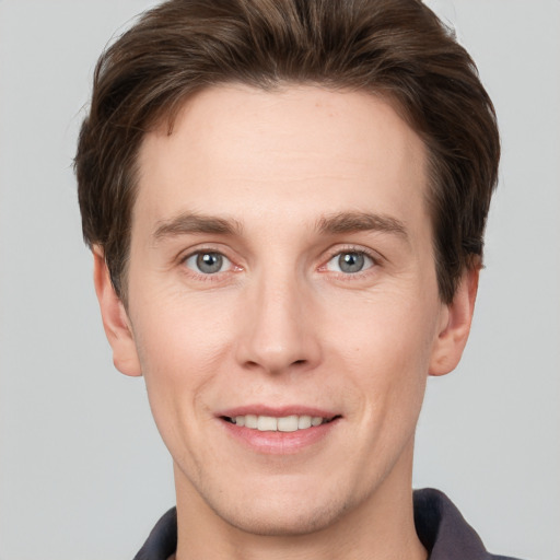 Joyful white young-adult male with short  brown hair and grey eyes