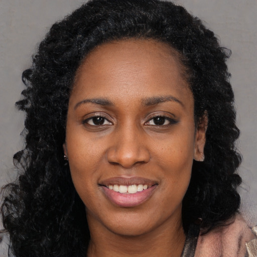 Joyful black young-adult female with long  black hair and brown eyes