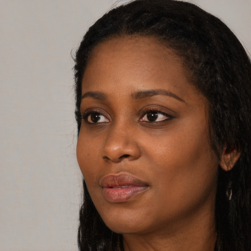Joyful black young-adult female with long  black hair and brown eyes