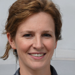 Joyful white adult female with medium  brown hair and blue eyes