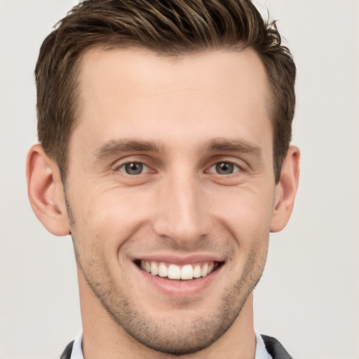 Joyful white young-adult male with short  brown hair and grey eyes