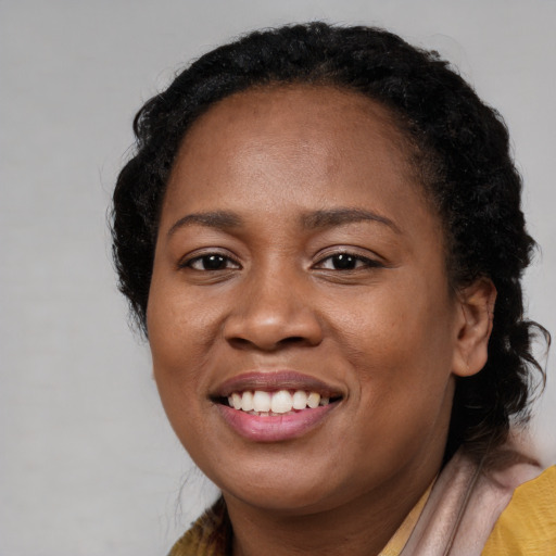 Joyful black young-adult female with long  brown hair and brown eyes