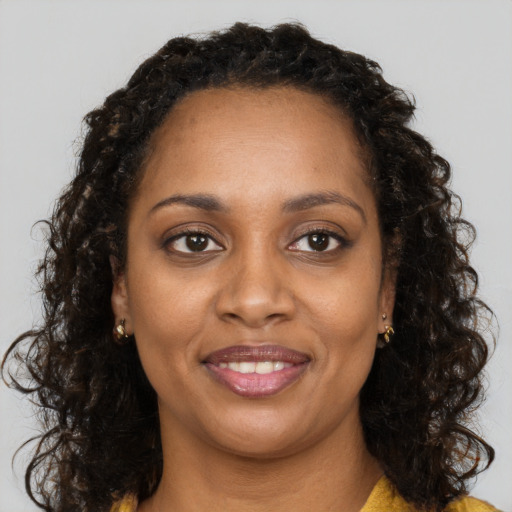 Joyful black young-adult female with long  brown hair and brown eyes