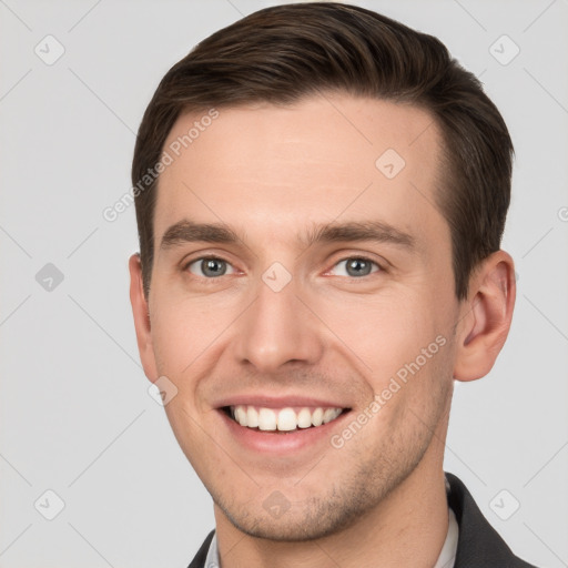 Joyful white young-adult male with short  brown hair and grey eyes