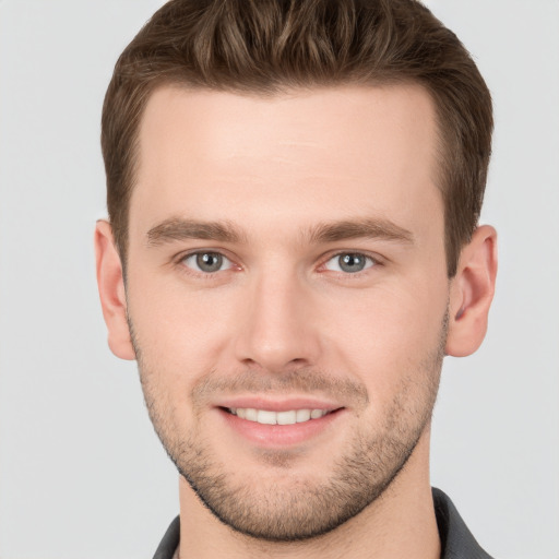 Joyful white young-adult male with short  brown hair and grey eyes