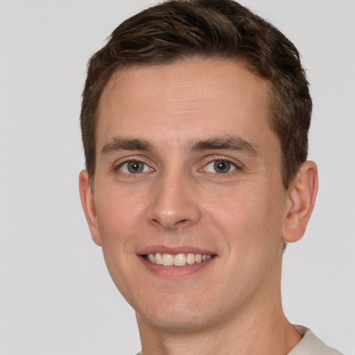 Joyful white young-adult male with short  brown hair and grey eyes