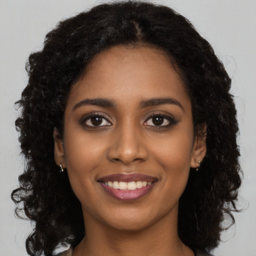 Joyful black young-adult female with long  black hair and brown eyes