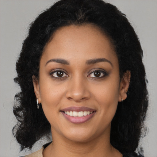 Joyful black young-adult female with long  black hair and brown eyes