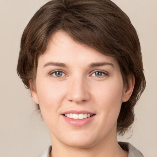 Joyful white young-adult female with medium  brown hair and grey eyes