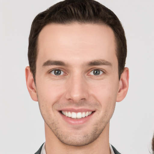 Joyful white young-adult male with short  brown hair and grey eyes