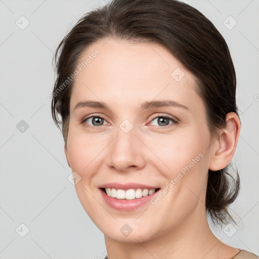 Joyful white young-adult female with medium  brown hair and grey eyes