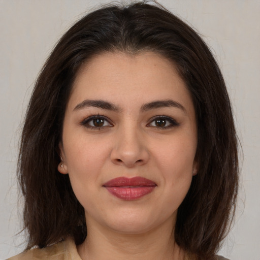 Joyful latino young-adult female with medium  brown hair and brown eyes
