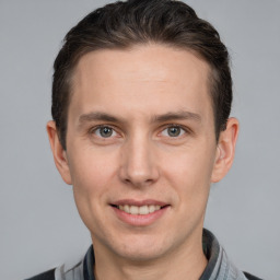 Joyful white young-adult male with short  brown hair and grey eyes