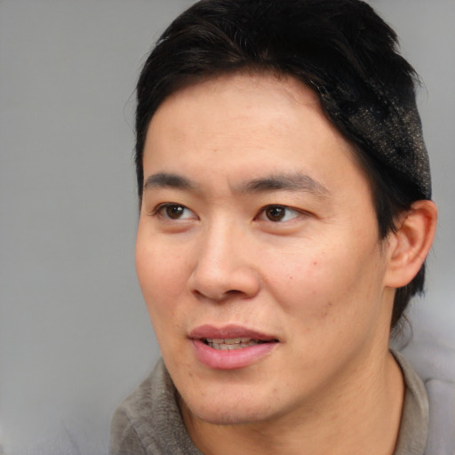 Joyful asian young-adult male with short  brown hair and brown eyes
