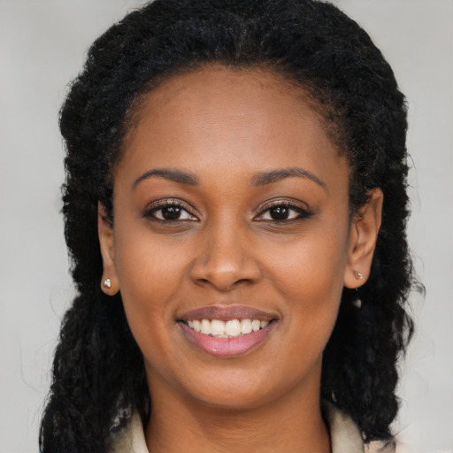 Joyful black young-adult female with long  brown hair and brown eyes