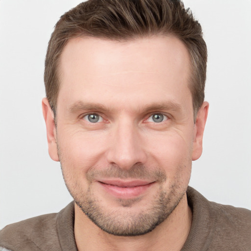 Joyful white young-adult male with short  brown hair and grey eyes