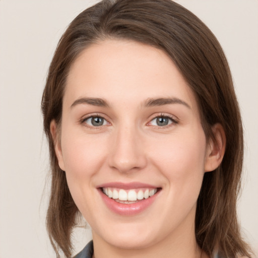 Joyful white young-adult female with medium  brown hair and grey eyes