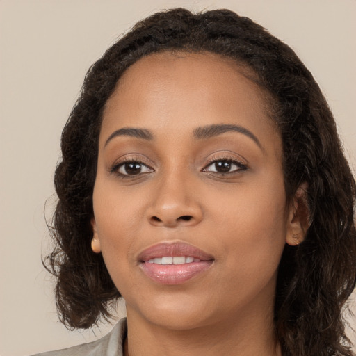 Joyful black young-adult female with long  brown hair and brown eyes