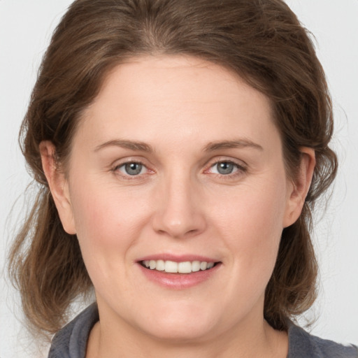 Joyful white young-adult female with medium  brown hair and grey eyes