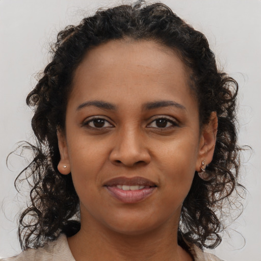 Joyful black young-adult female with long  brown hair and brown eyes