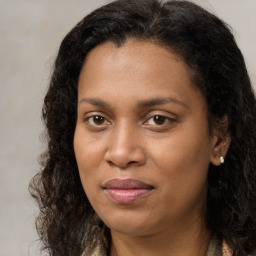 Joyful black young-adult female with long  brown hair and brown eyes