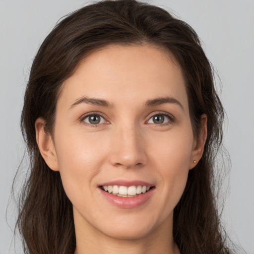 Joyful white young-adult female with long  brown hair and brown eyes