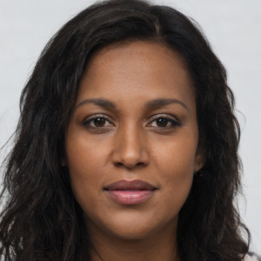 Joyful black young-adult female with long  brown hair and brown eyes