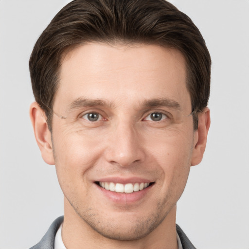 Joyful white young-adult male with short  brown hair and grey eyes