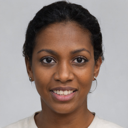 Joyful black young-adult female with short  black hair and brown eyes