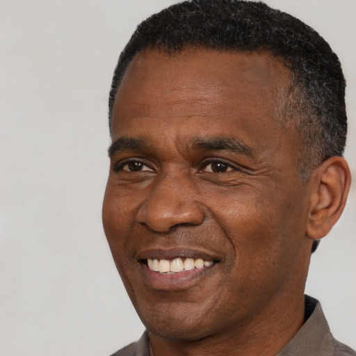 Joyful black adult male with short  black hair and brown eyes