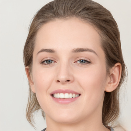 Joyful white young-adult female with medium  brown hair and grey eyes