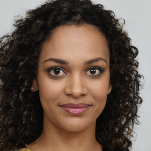 Joyful black young-adult female with long  brown hair and brown eyes