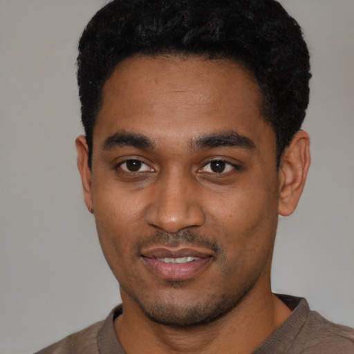 Joyful black young-adult male with short  black hair and brown eyes