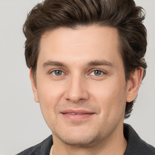 Joyful white young-adult male with short  brown hair and grey eyes