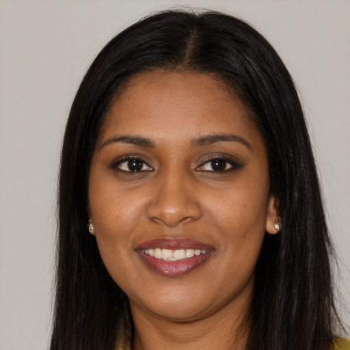 Joyful black young-adult female with long  brown hair and brown eyes