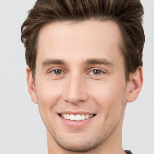 Joyful white young-adult male with short  brown hair and grey eyes