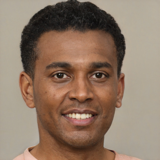 Joyful black young-adult male with short  brown hair and brown eyes