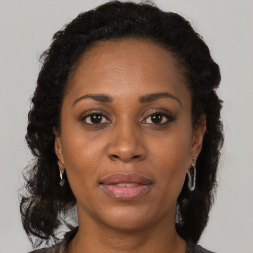 Joyful black adult female with long  brown hair and brown eyes